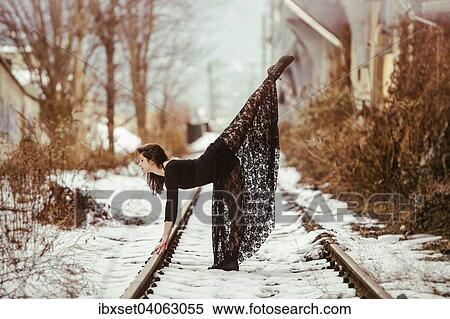 Stock Photography - Dancer striking a pose on railway tracks in winter. Fotosearch