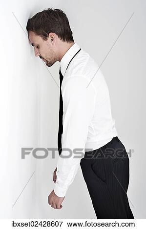 Desperate young man wearing a shirt and a tie standing with his head leaning against a wall View Large Photo Image Stock Photo - Desperate young man wearing a shirt and a tie standing with his head leaning against a wall. Fotosearch
