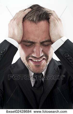 "Desperate young man wearing a suit holding his hands to his face, worried" View Large Photo Image Picture - "Desperate young man wearing a suit holding his hands to his face, worried". Fotosearch