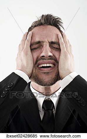 "Desperate young man wearing a suit holding his hands to his face, worried" View Large Photo Image Stock Photography - "Desperate young man wearing a suit holding his hands to his face, worried". Fotosearch