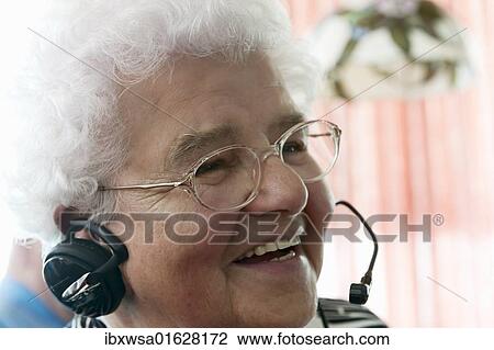 Stock Image - "Elderly woman on the phone, very pleased while using a headset for the first time, Germany, Europe". Fotosearch