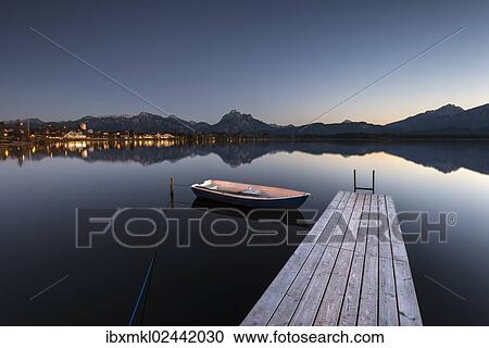 "Evening light at Hopfensee Lake with jetty and rowing boat, Allgaeu Alps at back, Fuessen, Ostallgaeu region, Allgaeu, Bavaria, Germany, Europe" View Large Photo Image Stock Image - "Evening light at Hopfensee Lake with jetty and rowing boat, Allgaeu Alps at back, Fuessen, Ostallgaeu region, Allgaeu, Bavaria, Germany, Europe". Fotosearch