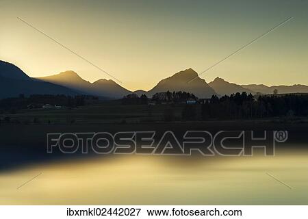 "Evening light on the shore of Hopfensee Lake, Allgaeu Alps at back, Fuessen, Ostallgaeu region, Allgaeu, Bavaria, Germany, Europe" View Large Photo Image Stock Photo - "Evening light on the shore of Hopfensee Lake, Allgaeu Alps at back, Fuessen, Ostallgaeu region, Allgaeu, Bavaria, Germany, Europe". Fotosearch