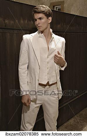 Fashion photo of a young man wearing a white suit standing in front of a wooden fence View Large Photo Image Stock Photography - Fashion photo of a young man wearing a white suit standing in front of a wooden fence. Fotosearch