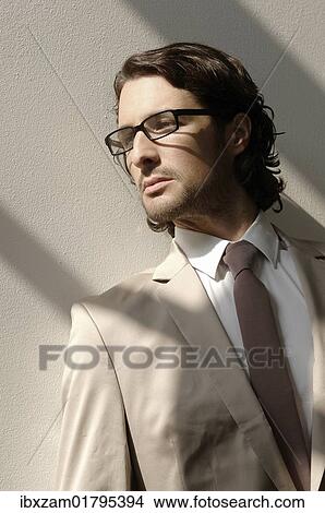 "Fashion shoot, a man wearing glasses and a suit in the sunlight" View Large Photo Image Picture - "Fashion shoot, a man wearing glasses and a suit in the sunlight". Fotosearch