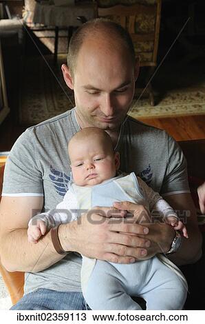 Stock Image - "Father, aged 28, holding a baby". Fotosearch