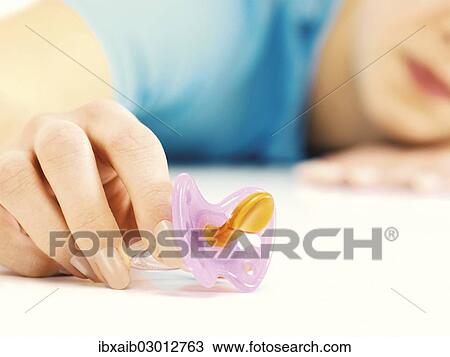 Stock Image - "Female hand holding a pacifier, symbolic image for family planning". Fotosearch