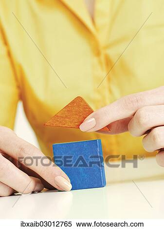 Stock Photography - Female hands putting two blocks together to form a house. Fotosearch