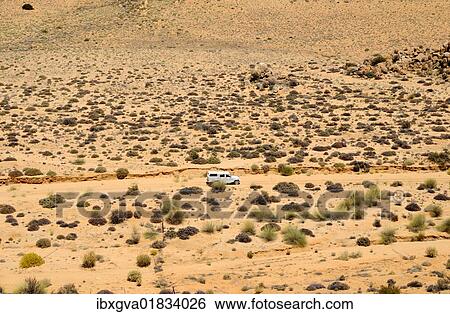 Stock Photograph - "Four-wheel-drive vehicle crossing the rugged, sparsely covered with low bushes, semi-desert landscape of Goegap Nature Reserve, Namaqualand, South Africa, Africa". Fotosearch