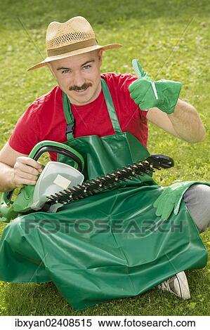 "Gardener holding a hedge trimmer while sitting on the lawn, making a thumbs-up gesture" View Large Photo Image Stock Photography - "Gardener holding a hedge trimmer while sitting on the lawn, making a thumbs-up gesture". Fotosearch