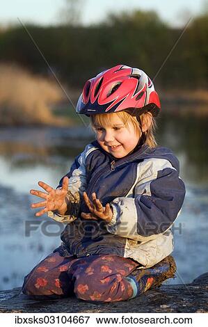 "Girl, 4, smiling and looking at her dirty hands which are covered with mud while sitting on a stone beside a pond, Crailsheim, Hohenlohe, Baden-Wurttemberg, Germany, Europe" View Large Photo Image Stock Photo - "Girl, 4, smiling and looking at her dirty hands which are covered with mud while sitting on a stone beside a pond, Crailsheim, Hohenlohe, Baden-Wurttemberg, Germany, Europe". Fotosearch