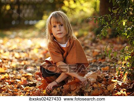 "Girl, 7 years old, sitting amidst autumn foliage at a playground" View Large Photo Image Stock Image - "Girl, 7 years old, sitting amidst autumn foliage at a playground". Fotosearch