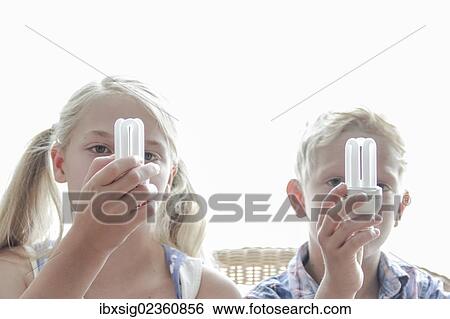 Girl and boy holding energy saving lamps in front of their faces View Large Photo Image Stock Photograph - Girl and boy holding energy saving lamps in front of their faces. Fotosearch