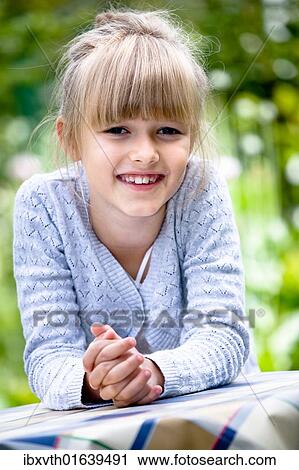 Stock Image - Girl at a table in the garden. Fotosearch