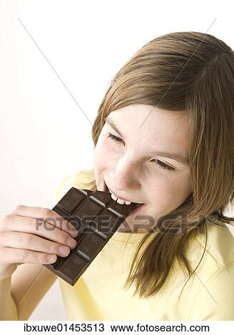 Girl biting into a chocolate bar with pleasure View Large Photo Image Stock Image - Girl biting into a chocolate bar with pleasure. Fotosearch