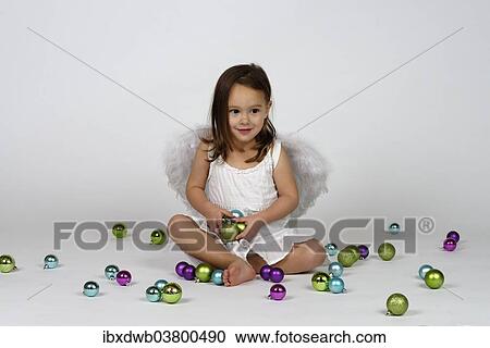 Girl dressed as an angel sits between Christmas baubles View Large Photo Image Stock Image - Girl dressed as an angel sits between Christmas baubles. Fotosearch