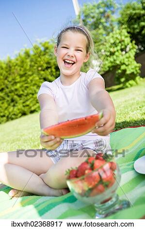 Girl eating a piece of watermelon in the garden View Large Photo Image Stock Photo - Girl eating a piece of watermelon in the garden. Fotosearch