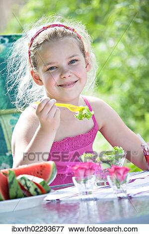 Girl eating salad at a garden table View Large Photo Image Stock Photo - Girl eating salad at a garden table. Fotosearch