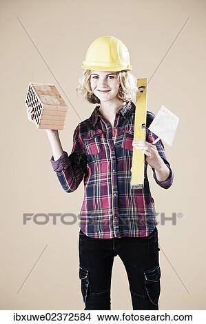 Girl holding a spirit level and a brick View Large Photo Image Picture - Girl holding a spirit level and a brick. Fotosearch