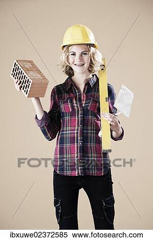 Girl holding a spirit level and a brick View Large Photo Image Stock Photography - Girl holding a spirit level and a brick. Fotosearch