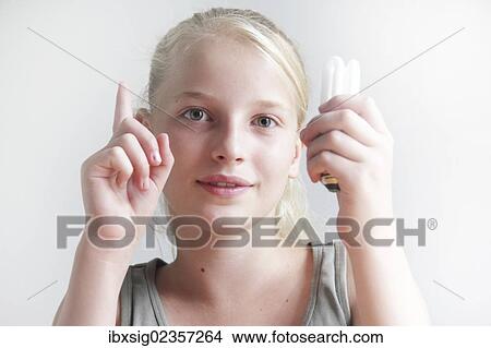 Girl holding an energy saving lamp in her hand and holding up her other hand View Large Photo Image Picture - Girl holding an energy saving lamp in her hand and holding up her other hand. Fotosearch