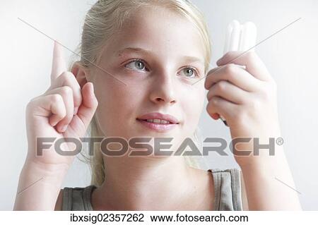 Girl holding an energy saving lamp in her hand and holding up her other hand View Large Photo Image Stock Image - Girl holding an energy saving lamp in her hand and holding up her other hand. Fotosearch