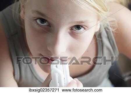 Stock Image - Girl holding an energy saving lamp in her hand. Fotosearch