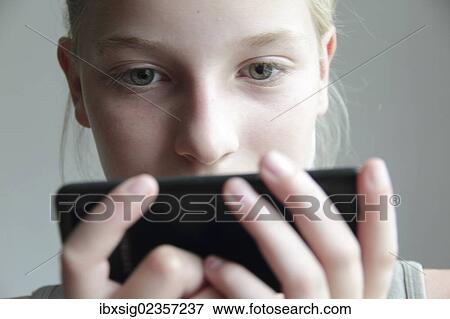 Girl looking at a smartphone View Large Photo Image Stock Photo - Girl looking at a smartphone. Fotosearch