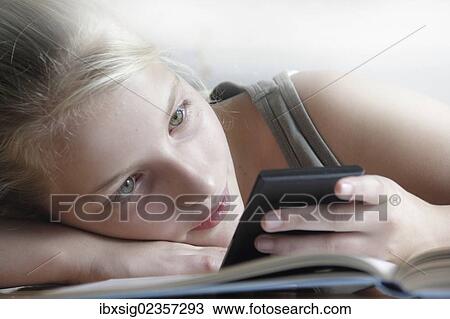 Girl looking at a smartphone with her homework lying in front of her View Large Photo Image Stock Image - Girl looking at a smartphone with her homework lying in front of her. Fotosearch
