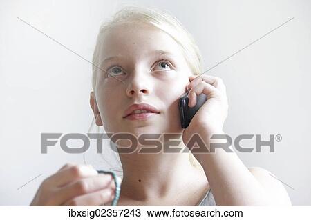 Stock Image - Girl looking up while talking on a mobile phone. Fotosearch