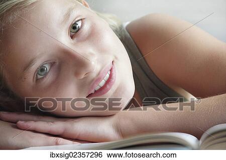 Stock Photograph - Girl lying in front of an opened book. Fotosearch