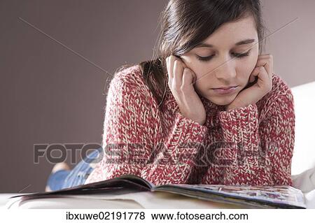 Stock Photo - Girl lying on a couch and reading a magazine. Fotosearch