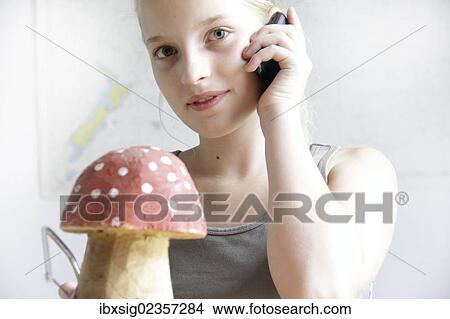 Girl making a fly agaric mushroom with the saw from a piece of wood and talking on a mobile phone View Large Photo Image Picture - Girl making a fly agaric mushroom with the saw from a piece of wood and talking on a mobile phone. Fotosearch
