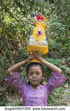 "Girl on the way to the temple, carrying offerings for a ceremony on her head, Bali, Indonesia, Asia" View Large Photo Image Picture - "Girl on the way to the temple, carrying offerings for a ceremony on her head, Bali, Indonesia, Asia". Fotosearch