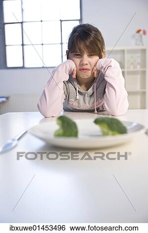 Girl sitting in front of a plate with broccoli in disgust View Large Photo Image Stock Photograph - Girl sitting in front of a plate with broccoli in disgust. Fotosearch