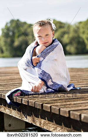 "Girl sitting on jetty at lakeside, wrapped in a towel" View Large Photo Image Stock Image - "Girl sitting on jetty at lakeside, wrapped in a towel". Fotosearch