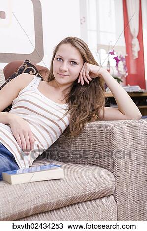 "Girl sitting on sofa, a book next to her" View Large Photo Image Stock Image - "Girl sitting on sofa, a book next to her". Fotosearch