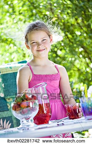 Stock Image - Girl standing at a garden table. Fotosearch