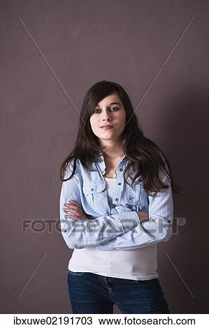 Girl standing with her arms folded in front of a wall View Large Photo Image Stock Image - Girl standing with her arms folded in front of a wall. Fotosearch