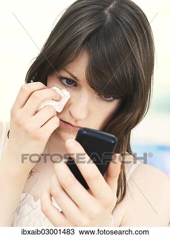 "Girl, teenager, holding a mobile phone, looking sad, looking at text message" View Large Photo Image Stock Image - "Girl, teenager, holding a mobile phone, looking sad, looking at text message". Fotosearch