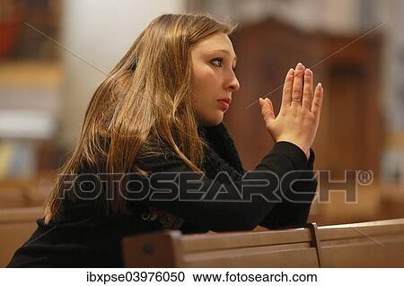 Stock Image - "Girl, teenager, praying in a church, Menton, Alpes-Maritimes, Provence-Alpes-Cote d'Azur, France, Europe". Fotosearch