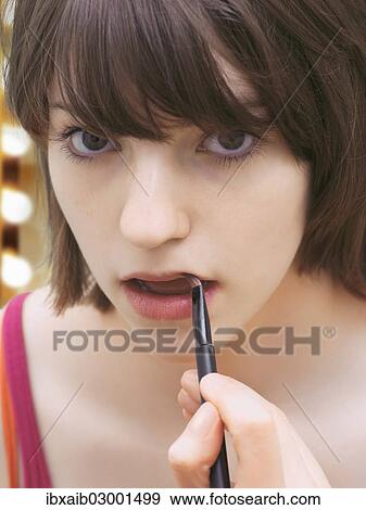 Stock Photo - "Girl, teenager, wearing make-up, applying lip gloss". Fotosearch