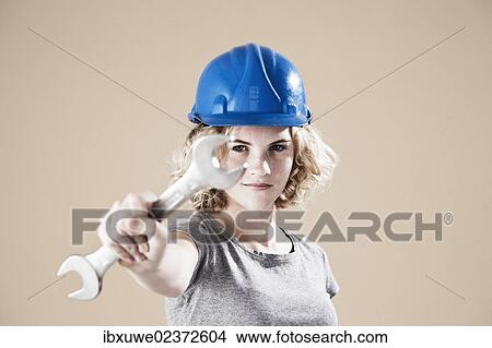 Girl wearing a hard hat and holding a spanner View Large Photo Image Picture - Girl wearing a hard hat and holding a spanner. Fotosearch
