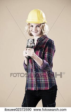 Girl wearing a hard hat and holding a drill View Large Photo Image Stock Image - Girl wearing a hard hat and holding a drill. Fotosearch
