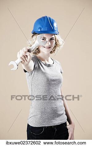 Girl wearing a hard hat and holding a spanner View Large Photo Image Stock Image - Girl wearing a hard hat and holding a spanner. Fotosearch