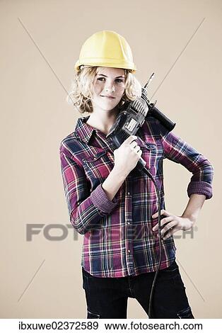 Girl wearing a hard hat and holding a drill View Large Photo Image Stock Photo - Girl wearing a hard hat and holding a drill. Fotosearch