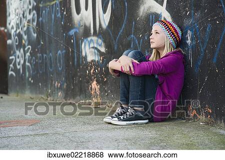 Girl wearing a knitted cap sitting in front of a wall with graffiti View Large Photo Image Stock Photo - Girl wearing a knitted cap sitting in front of a wall with graffiti. Fotosearch