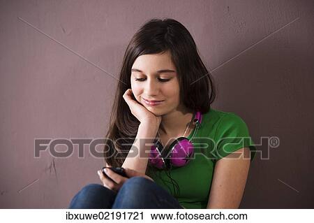 Girl wearing headphones and using a cell phone View Large Photo Image Stock Image - Girl wearing headphones and using a cell phone. Fotosearch