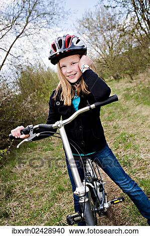 Stock Image - Girl with a cycling helmet and a bike. Fotosearch