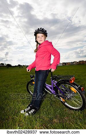 Stock Photo - Girl with a cycling helmet and a bike. Fotosearch